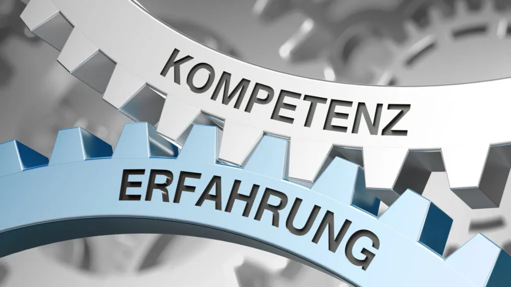 Zwei ineinandergreifende Zahnräder mit den Aufschriften Kompetenz und Erfahrung