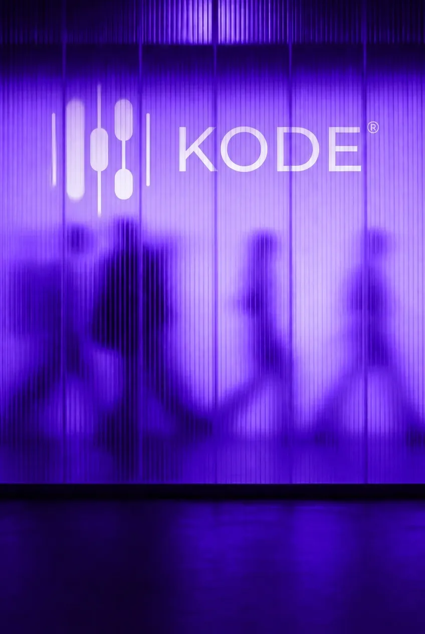 Menschen hinter einer beleuchteten Rippenglaswand mit KODE® Logo